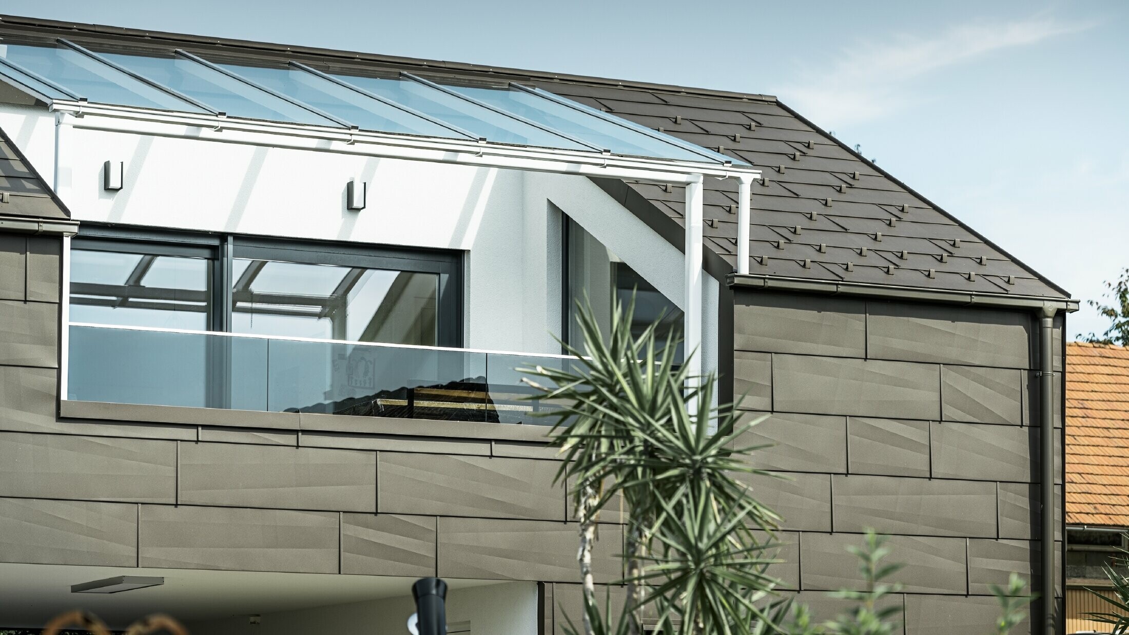 Prizidek s strešno teraso, obložen s celovitim sistemom PREFA, na strehi in fasadi je bil uporabljen strešni in fasadni panel FX.12. Za odvodnjavanje strehe je uporabljen pravokotni žleb PREFA z iztočno cevjo PREFA in obsežno dodatno opremo v rjavi barvi.
