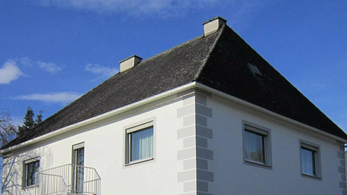Hiša s čopasto streho v Avstriji pred obnovo strehe z elementi Prefalz in strešnimi ploščami PREFA