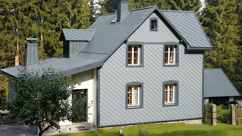 Enodružinska hiša ob gozdu z vremensko odporno aluminijasto fasado PREFA v svetlo sivi barvi.