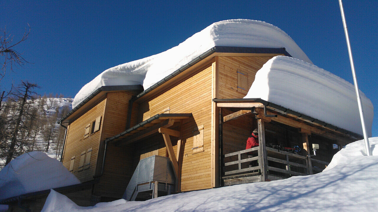 Gorska koča Capanna Buffalora z več centimetri snega na strehi. 