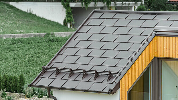 Streha s strešnimi ploščami PREFA R.16 v orehovo rjavi barvi in s sistemom snegolovov.