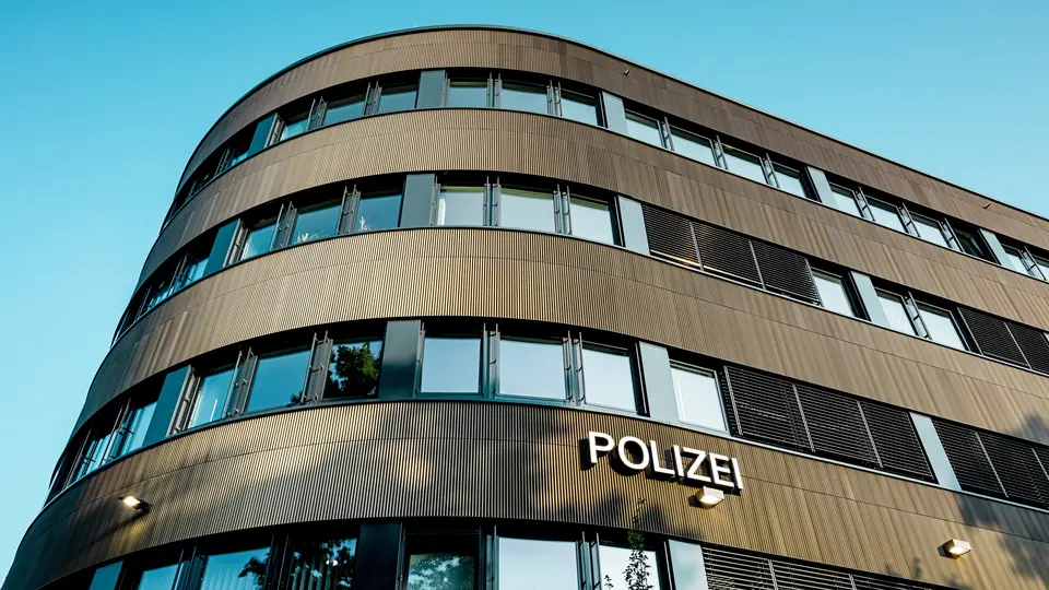 Dramatičen pogled od spodaj na ukrivljeno novo stavbo policijske postaje 43 v Hamburgu: izrazita PREFA aluminijasta fasada iz eloksiranih ekstrudiranih profilov »zobčasti profil« v srednje bronasti barvi privlači vse poglede kot arhitekturni magnet. Fina, ritmična struktura ustvarja dinamične prehode svetlobe in sence ter poudarja tekoče zaobljenosti stavbe. PREFA aluminij prepriča z visoko odpornostjo proti vremenskim vplivom, zaščito pred korozijo in dolgo življenjsko dobo – trajnostna rešitev, ki zahteva malo vzdrževanja, za natančno, moderno fasadno arhitekturo. 