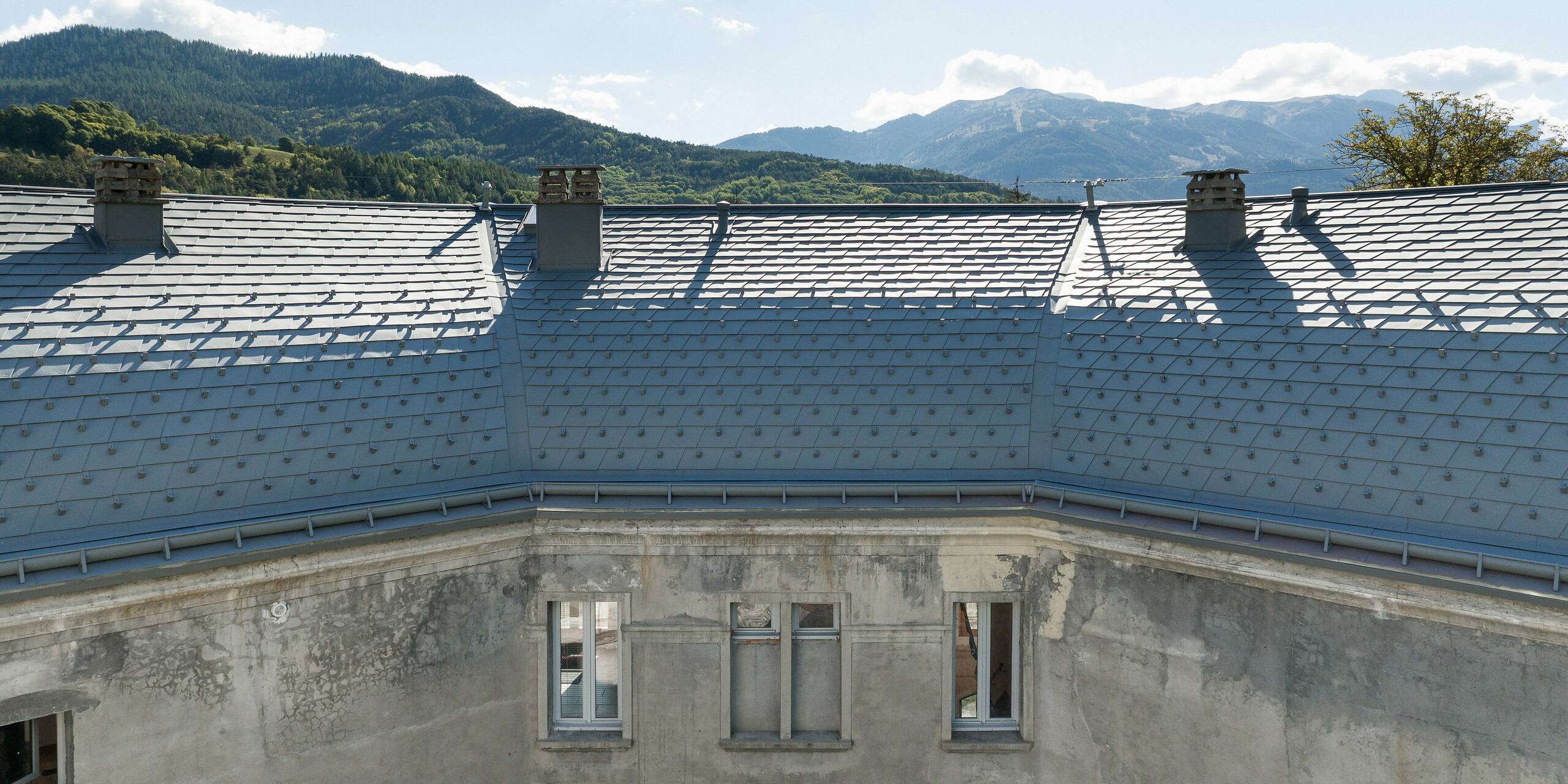 Velika strešna površina hiše na posestvu v kraju Barcelonnette v Franciji je bila obnovljena s strešnimi skodlami PREFA v P.10 svetlo sivi barvi.