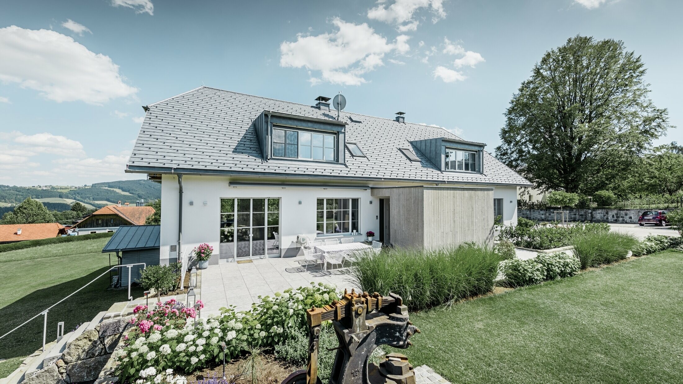 Klasična enodružinska hiša, dvokapnica; prenova strehe s strešnimi skodlami PREFA v barvi kamnito siva z lepo urejenim vrtom in razkošno teraso.