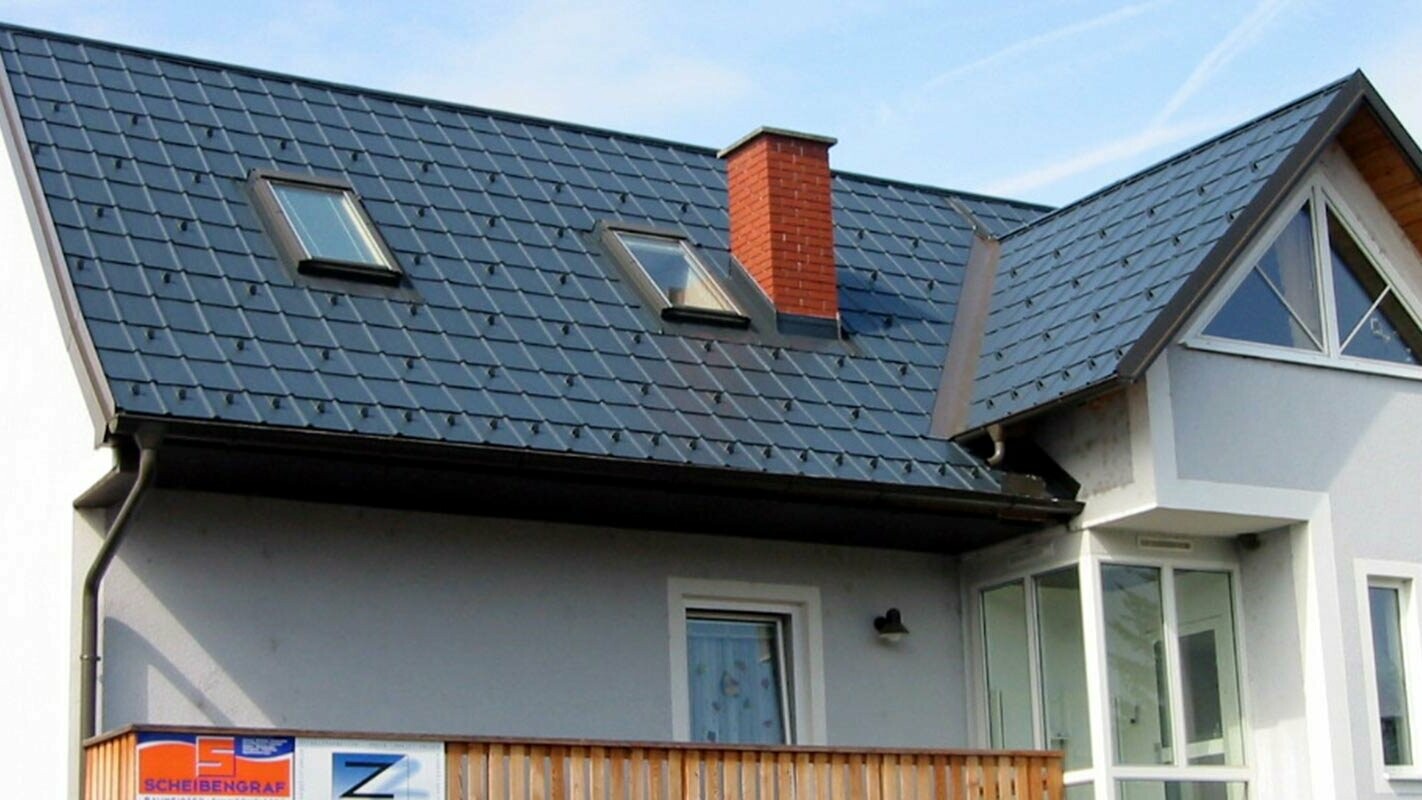 Enodružinska hiša z dvokapno streho in modro fasado – novo obnovljena streha s kritino PREFA