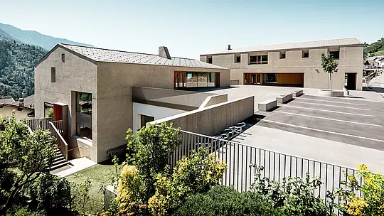 Izobraževalni center Riffian na Južnem Tirolskem izstopa z dvema markantnima stavbnima objektoma, ki ju v objemu alpske pokrajine krasijo strešni rombi PREFA 44 × 44 v barvi P.10 bronasta. Natančno izvedena aluminijasta strešna kritina poudarja čiste arhitekturne linije, zagotavlja dolgotrajno zaščito pred vremenskimi vplivi ter povezuje vrtec, osnovno šolo in sončno šolsko dvorišče v skladno sodobno arhitekturno celoto.