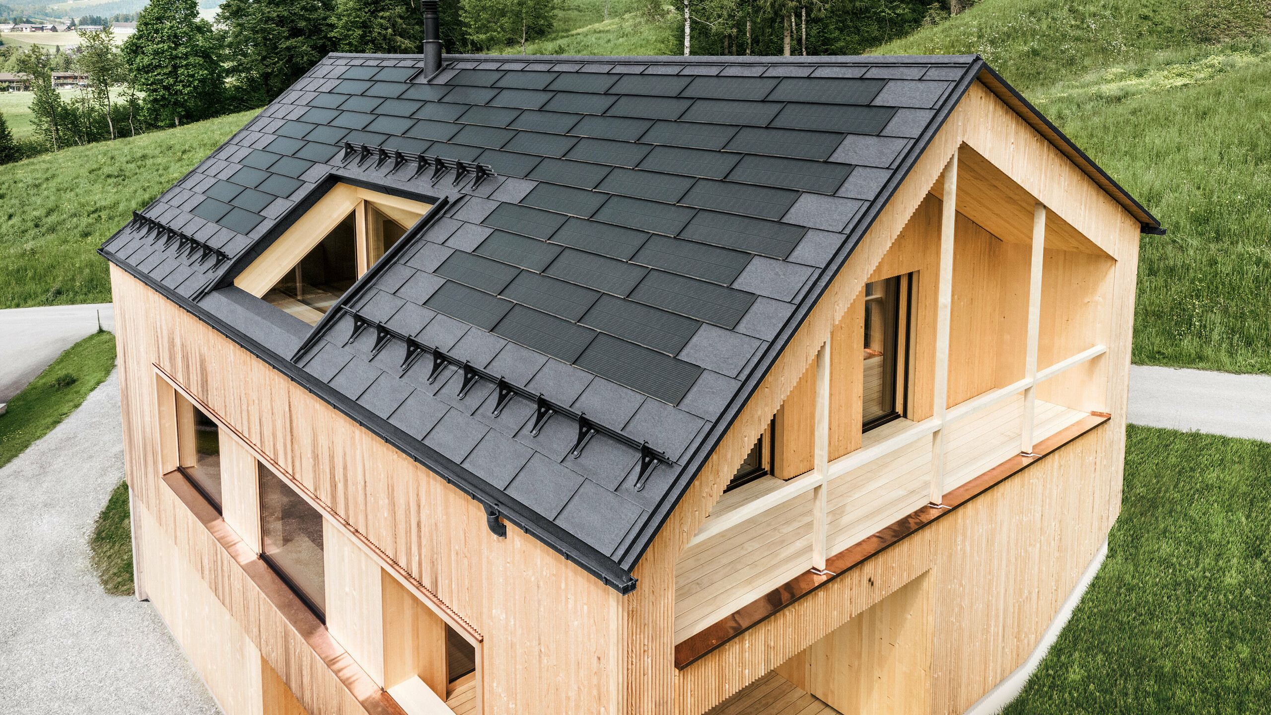 Einfamilienhaus im österreichischen Ort Egg mit der PREFA Solardachplatte und der Dachplatte R.16 in Steingrau, kombiniert mit einer Holzfassade