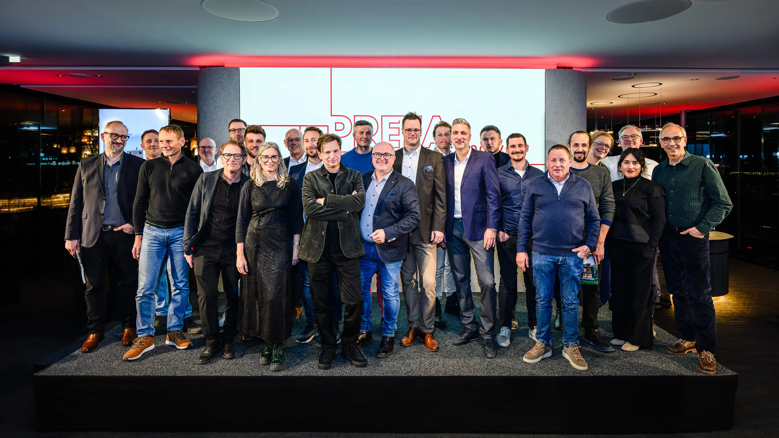 Skupinska fotografija arhitektov, projektantov in izvajalcev na odru PREFARENZEN predstavitve 2026 v k47.wien – močan simbol skupnosti, ustvarjalnosti in napredne arhitekture. Pred svetlečim logotipom PREFARENZEN stojijo oblikovalci, ki stojijo za impresivnimi projekti z aluminijem PREFA. Prizor odraža ponos, inovativnost in sodelovanje. Izdelki PREFA ponujajo trajne, vremensko odporne rešitve z estetsko vrednostjo – idealne za sodobne arhitekturne koncepte. Navdihujoč večer, poln izmenjave, vizij in močnih partnerstev. 