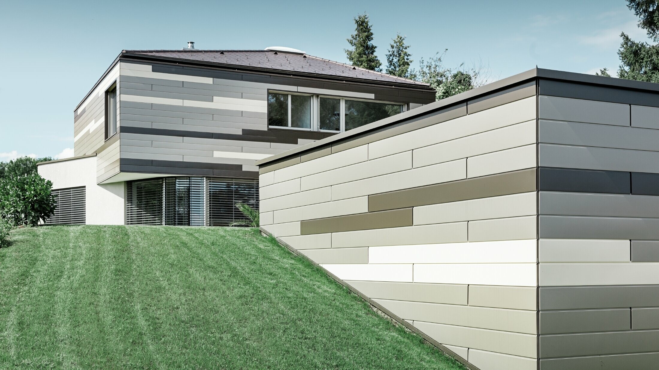 Sodobna enodružinska z ravno streho in pokrito teraso z individualno oblikovano aluminijasto fasado iz elementov PREFA Siding v rjavi, bronasti in slonokoščeni barvi