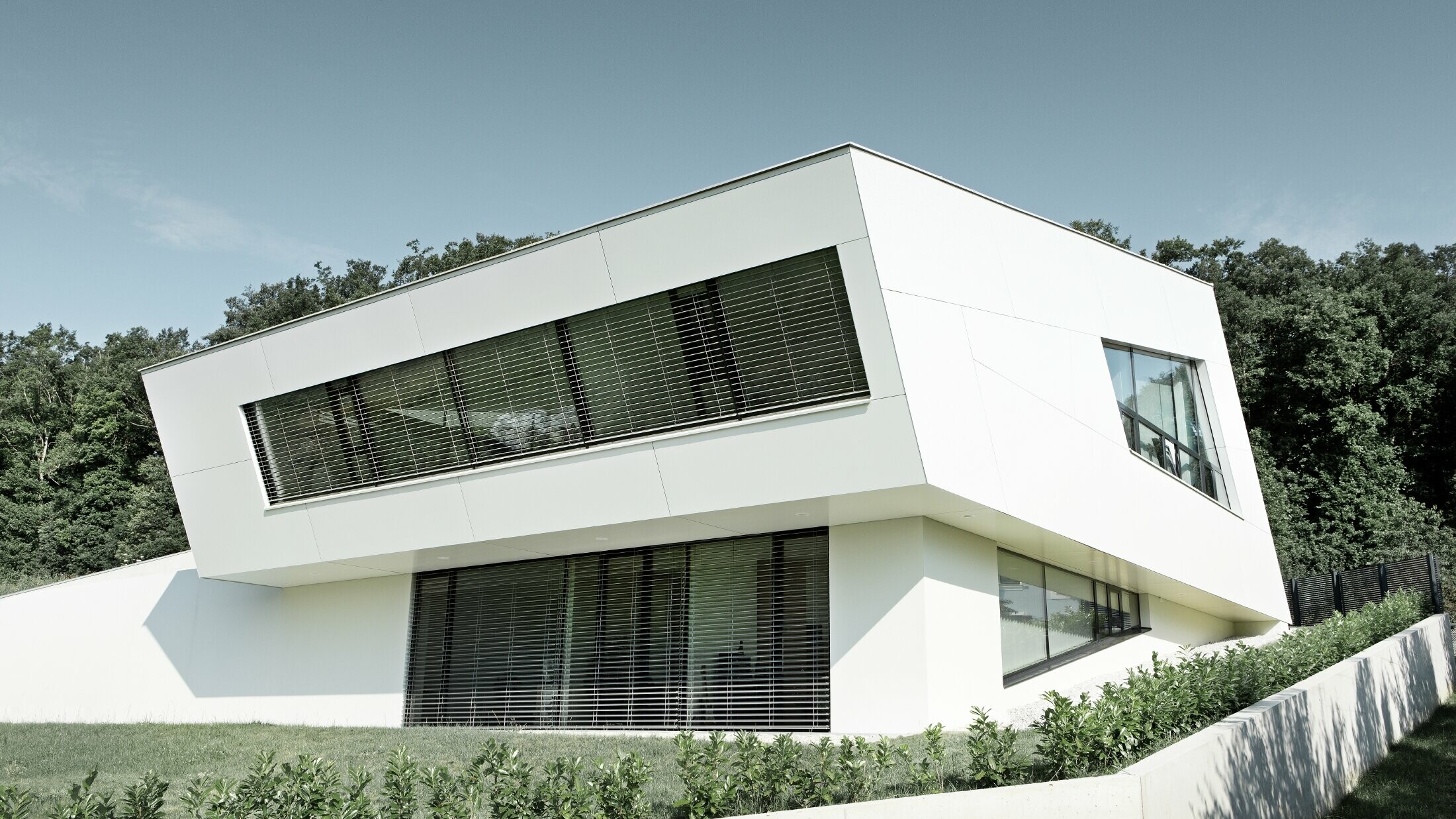 Zelo moderna družinska hiša s fasado iz belih kompozitnih plošč PREFA in velikimi okni