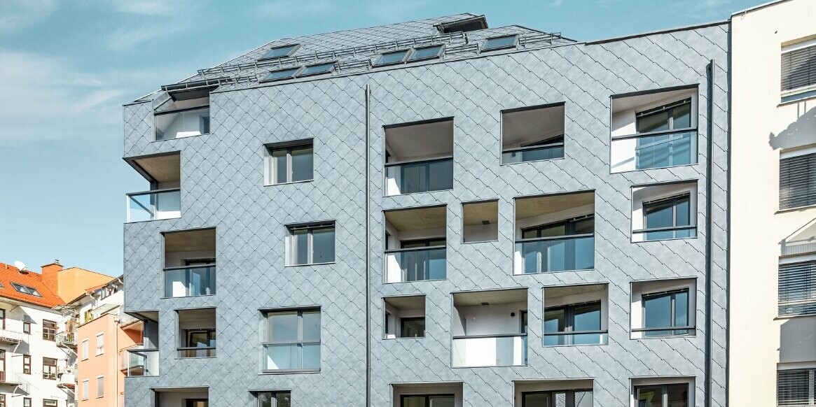 Blick auf das Wohnhaus in Graz, welches die Fassade gedeckt mit der PREFA Raute 44 × 44 in der Farbe P.10 Steingrau.