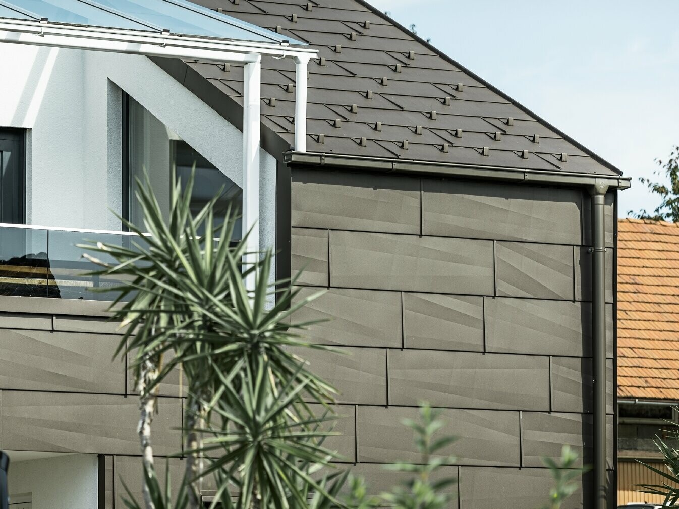 Prizidek s strešno teraso s celovitim sistemom PREFA, na strehi in fasadi so uporabljeni strešni in fasadni paneli PREFA FX.12. Poleg tega je uporabljen pravokotni žleb PREFA z odtočno cevjo in bogato paleto dodatnih elementov v rjavi barvi za odvodnjavanje strehe.