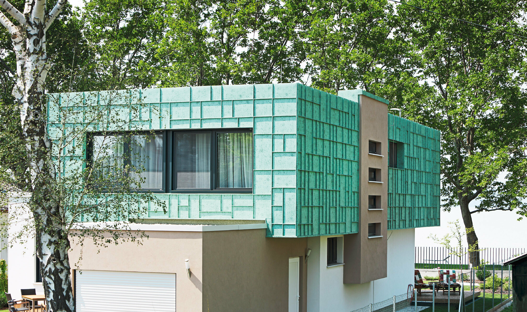 Moderna enodružinska hiša s fasado, ki je varna pred močnimi sunki vetra, obloženo s sistemom PREFALZ v patinirano zeleni barvi P.10