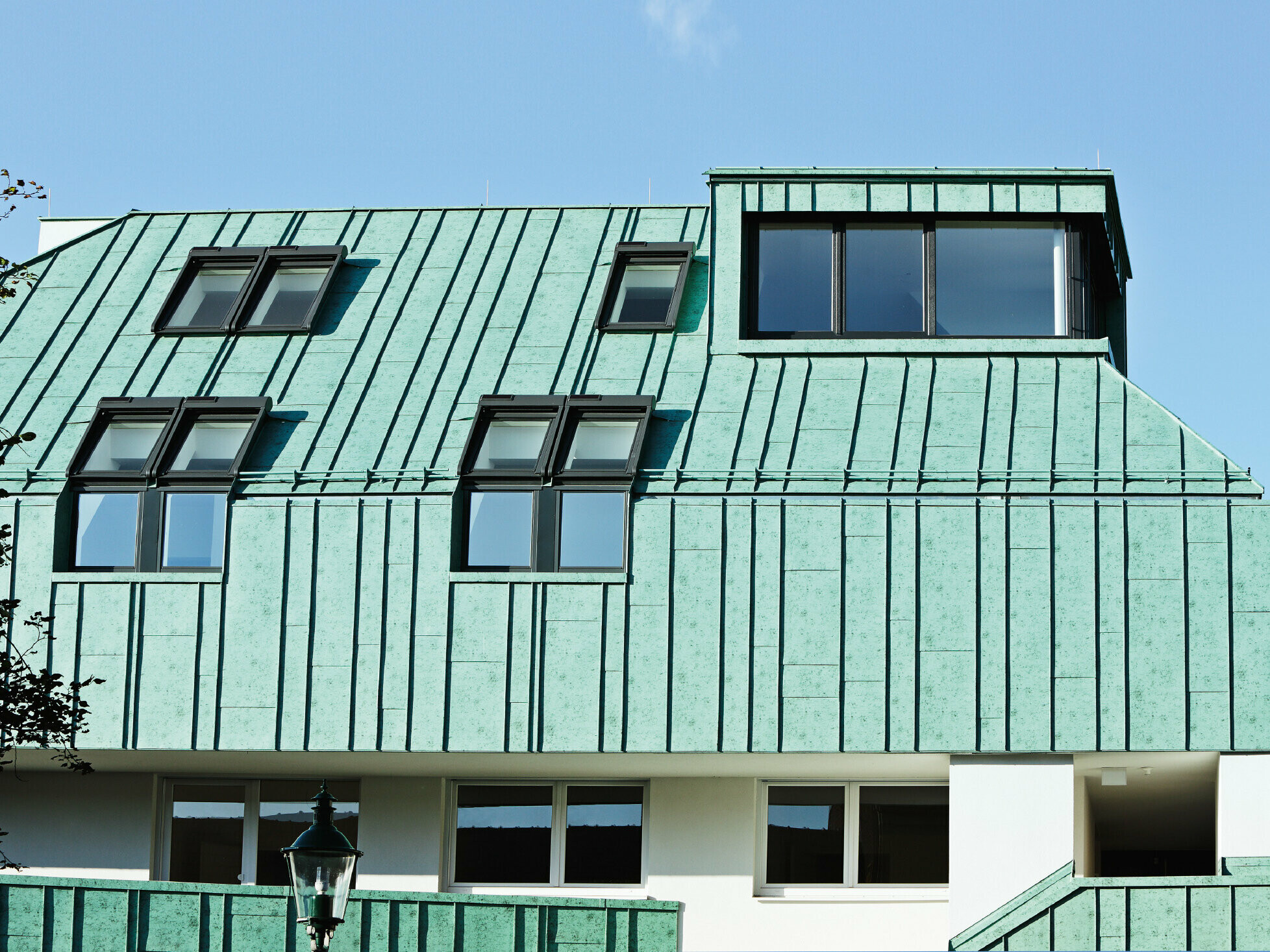 Oblikovanje strehe in fasade PPREFALZ z barvnimi odtenki PREFA v patinirano zeleni barvi z različnimi širinami trakov