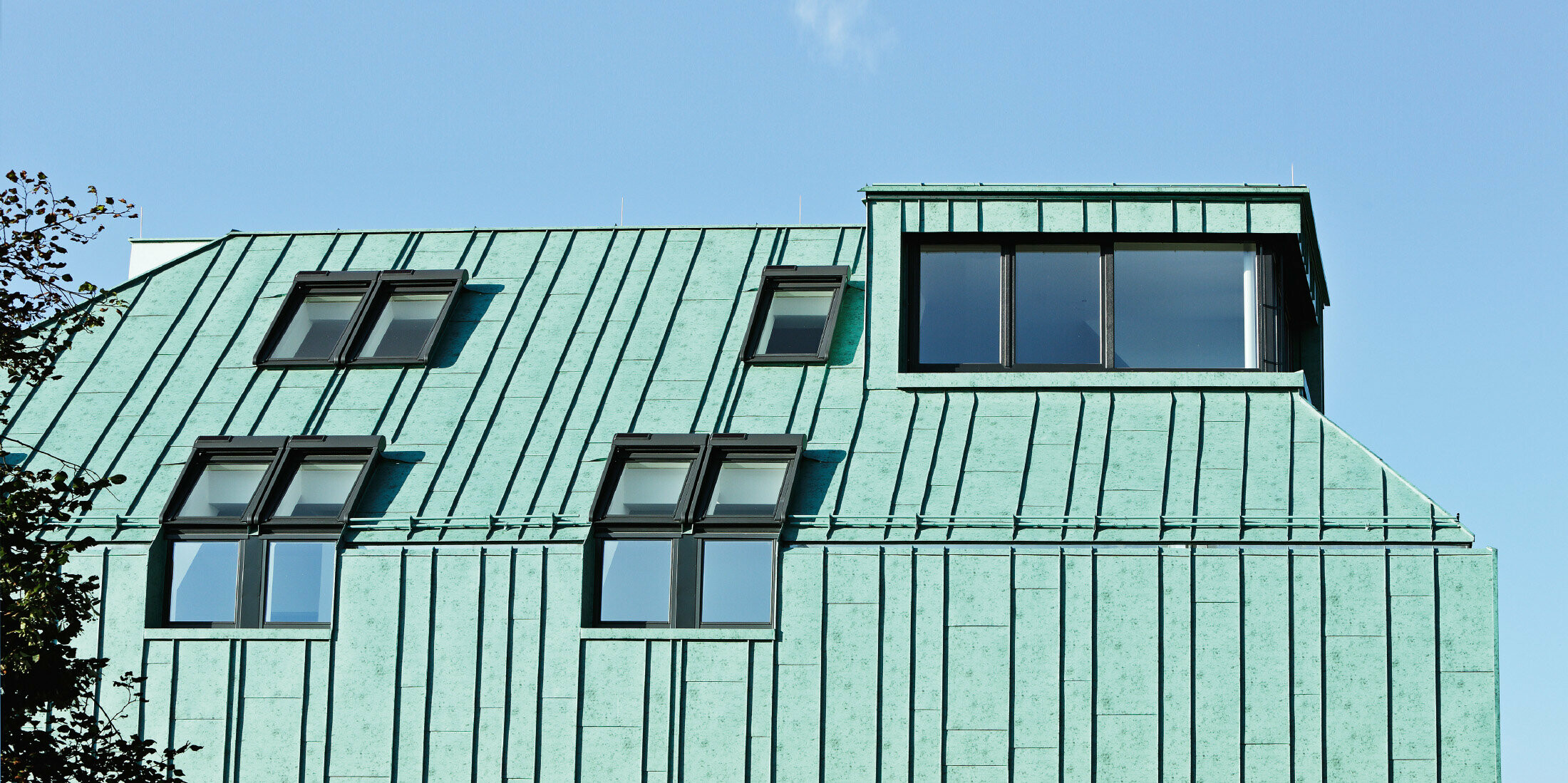 Oblikovanje strehe in fasade PPREFALZ z barvnimi odtenki PREFA v patinirano zeleni barvi z različnimi širinami trakov