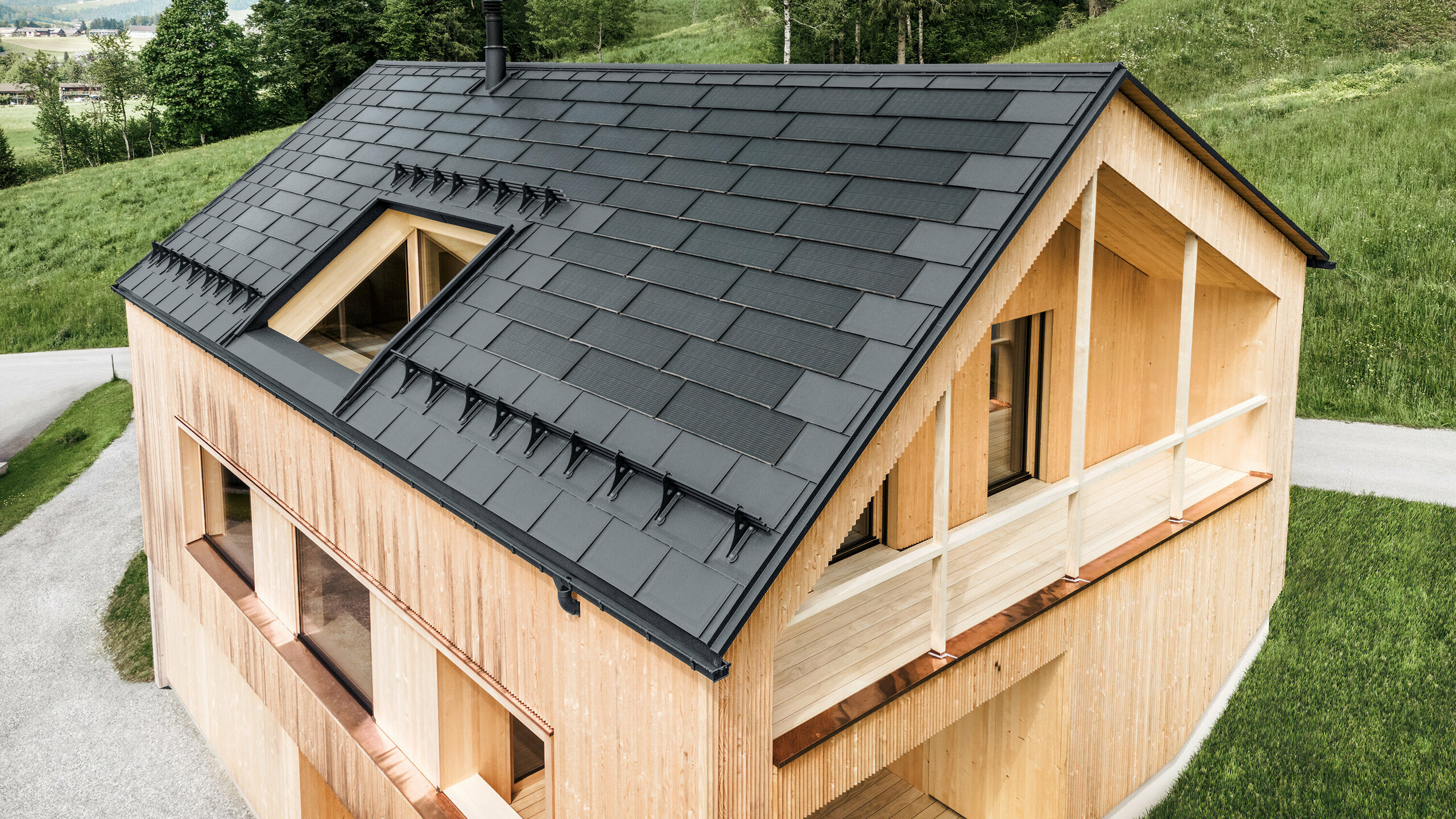 Einfamilienhaus im österreichischen Ort Egg mit der PREFA Solardachplatte und der Dachplatte R.16 in Dunkelgrau, kombiniert mit einer Holzfassade