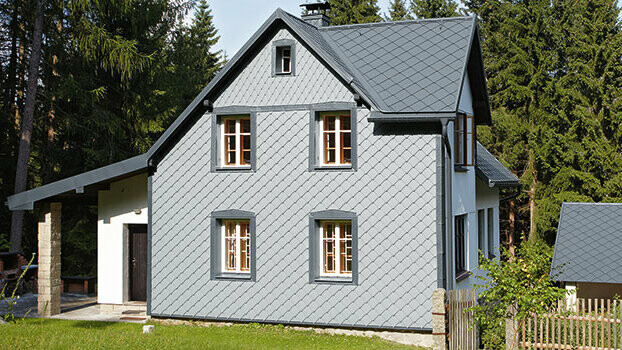 Enodružinska hiša s celovitim sistemom PREFA – fasada je obložena s fasadnimi rombi PREFA 29 v svetlo sivi barvi.