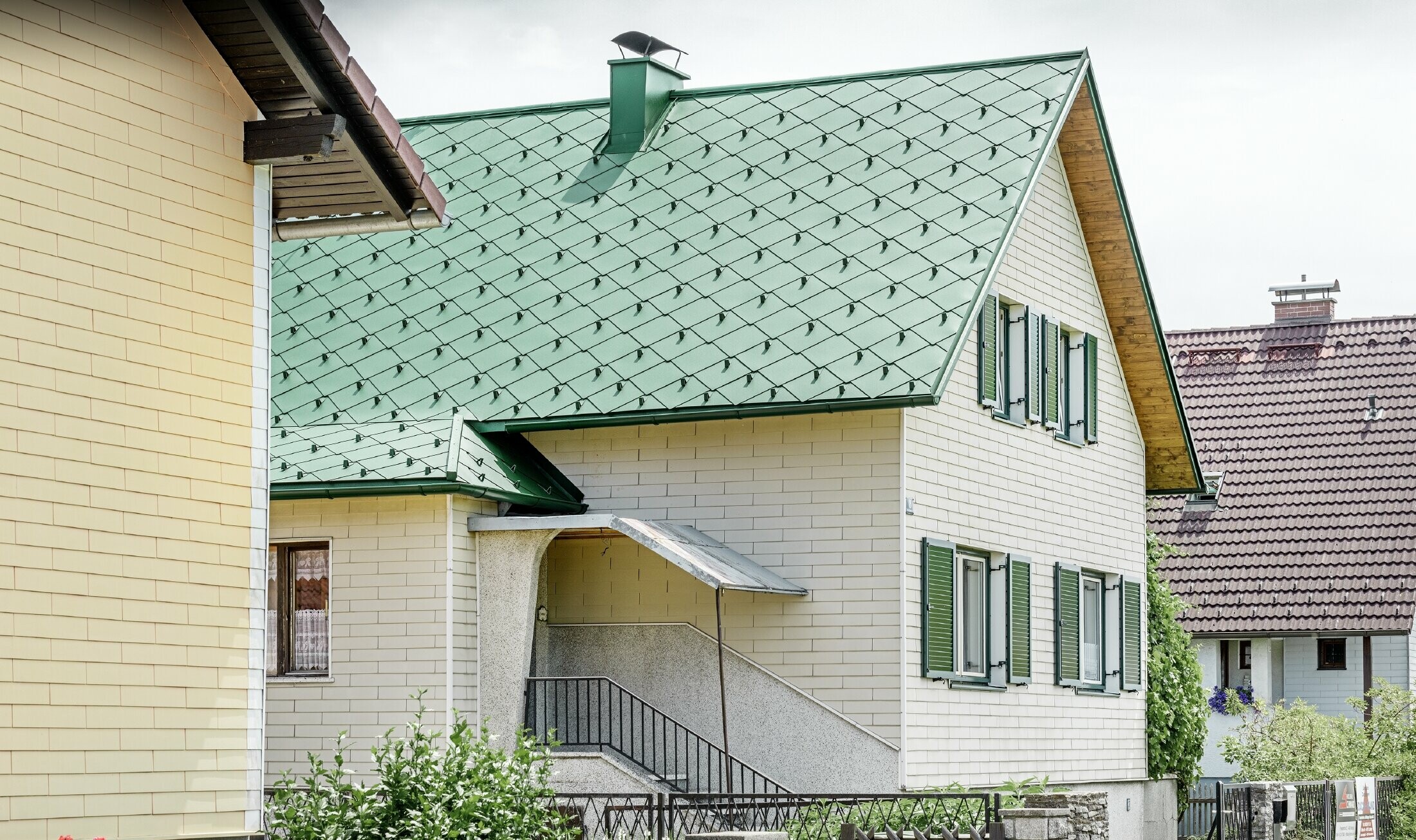 Klasična enodružinska hiša z dvokapno streho iz aluminija v močvirno zeleni barvi z zelenimi naoknicami