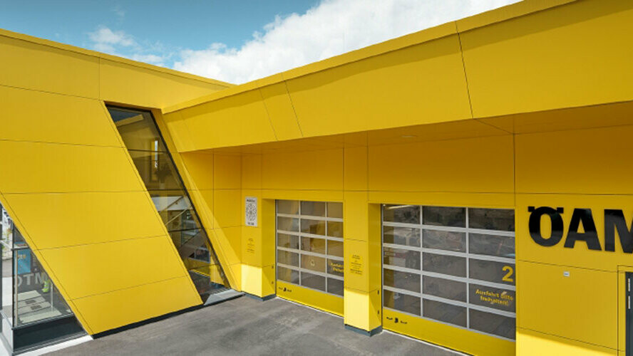 Postojanka ÖAMTC s kompozitnimi ploščami PREFA v repično rumeni barvi, ki so bile vgrajene kot obešena prezračevana fasada.