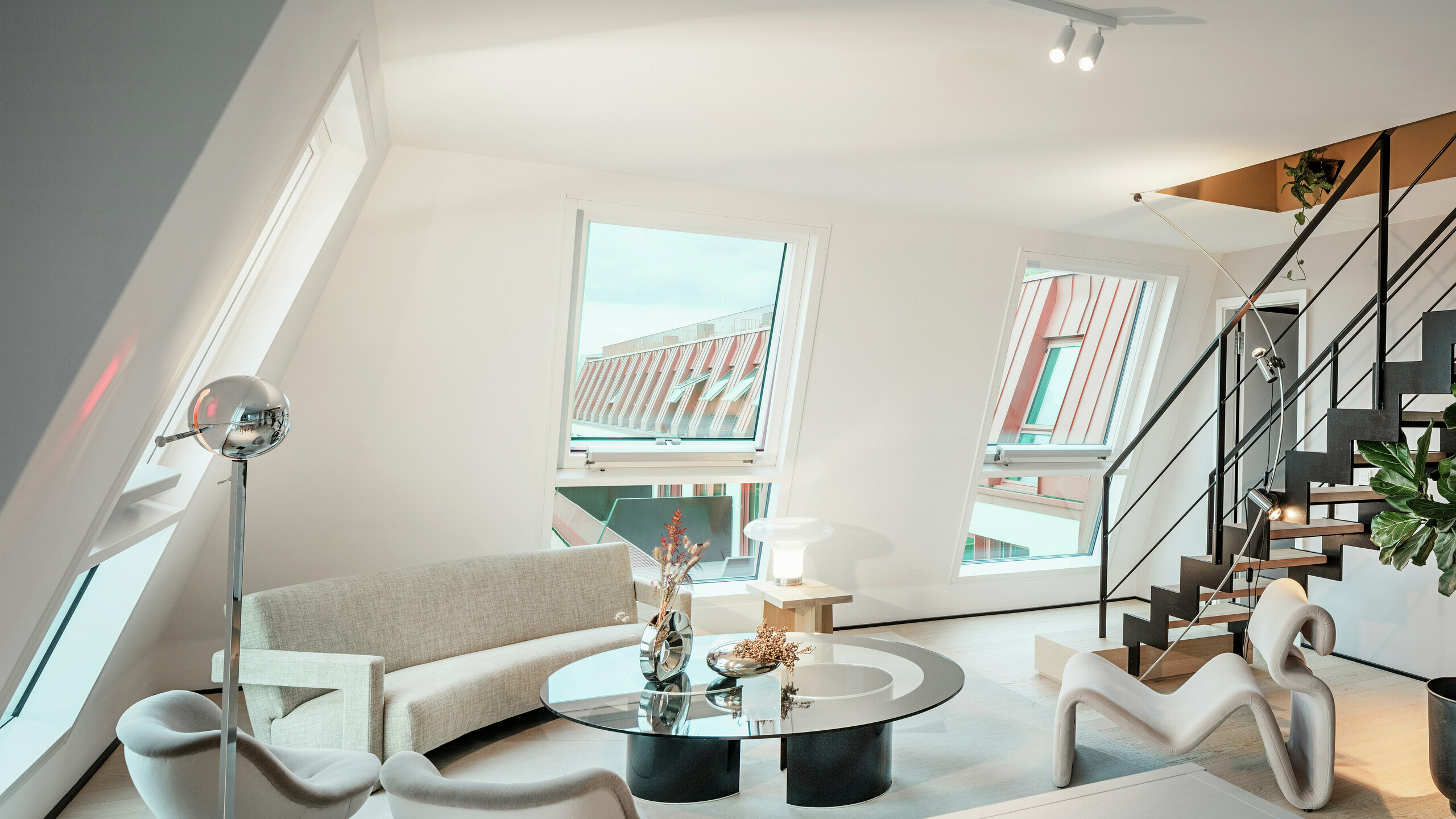 Pogled v notranjost svetlega penthousa v stanovanjskem objektu Van B v Münchnu s pogledom na visokokakovostno aluminijasto streho PREFALZ v posebni barvi IGP Orange HDP. Velika okna prepuščajo veliko dnevne svetlobe in poudarjajo sodoben koncept bivanja. Jasne linije, dizajnersko pohištvo in natančna izdelava strešnih povezav kažejo, kako je mogoče kakovostno in elegantno arhitekturo uresničiti ne le zunaj, temveč tudi znotraj.