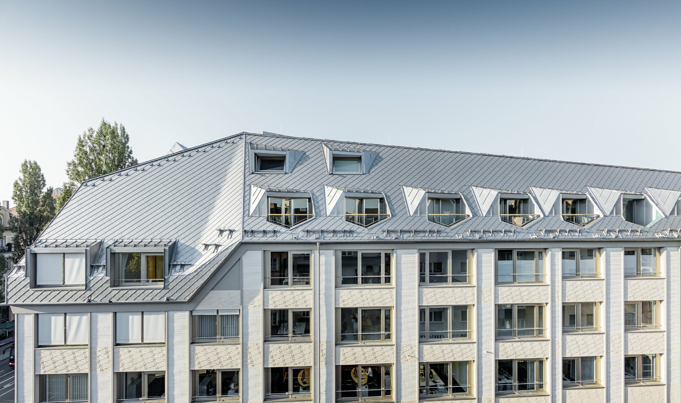 Sanirana mansardna stanovanja z velikopoteznimi odprtimi galerijami v stanovanjskem in poslovnem objektu na vogalu Leopoldstraße in Hohenzollernstraße v Münchnu, s strešno kritino iz strešnih rombov PREFA