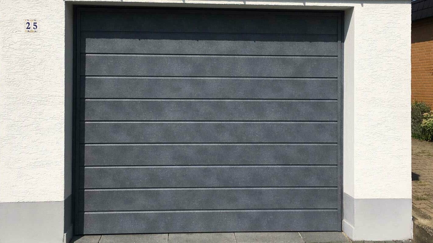 Garažna vrata, obložena z vodoravno položenimi elementi PREFA Siding v kamnito sivi barvi