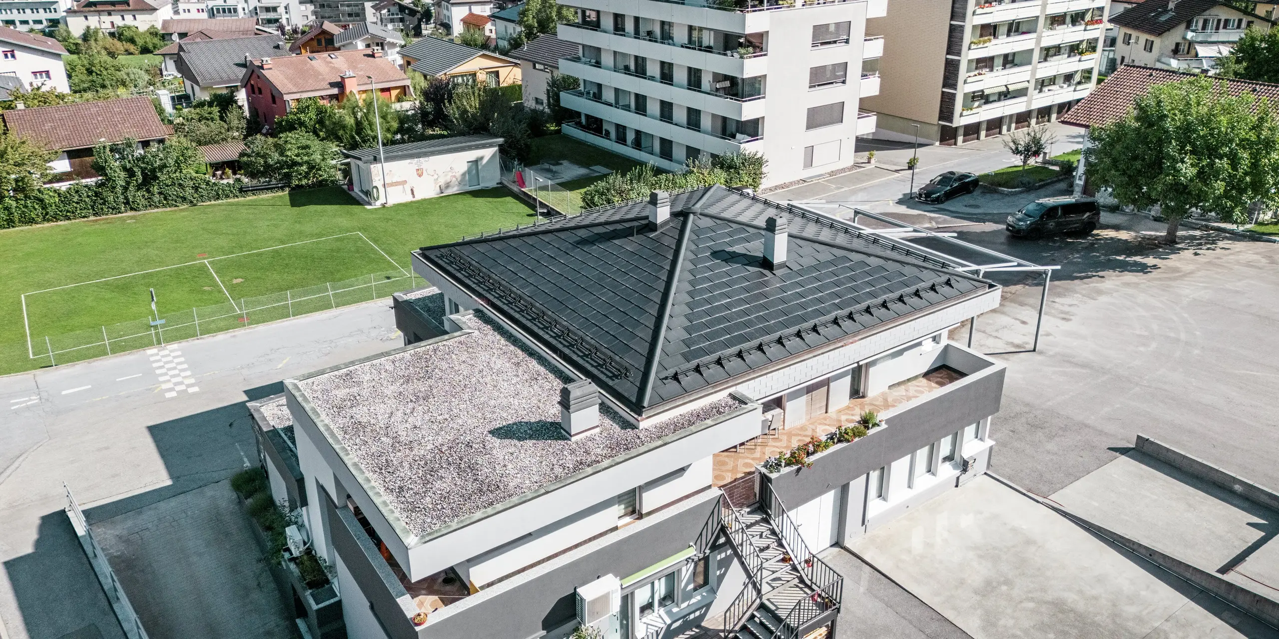 Das moderne Zeltdach der Weinkellerei Leukersonne in Susten (CH) mit PREFA Solardachplatte und Dachplatte R.16 in P.10 Schwarz - langlebig, witterungsbeständig und energieeffizient.