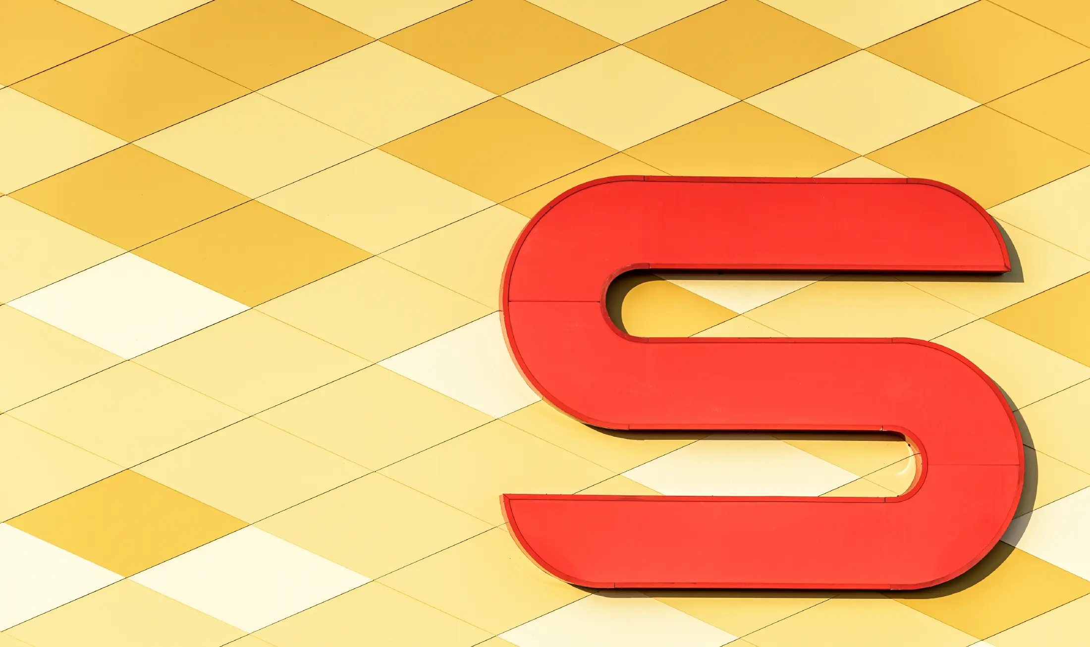 Poslovalnica Spar z aluminijasto fasado v rumeno-oranžnih karo vzorcih in logotipom Spar