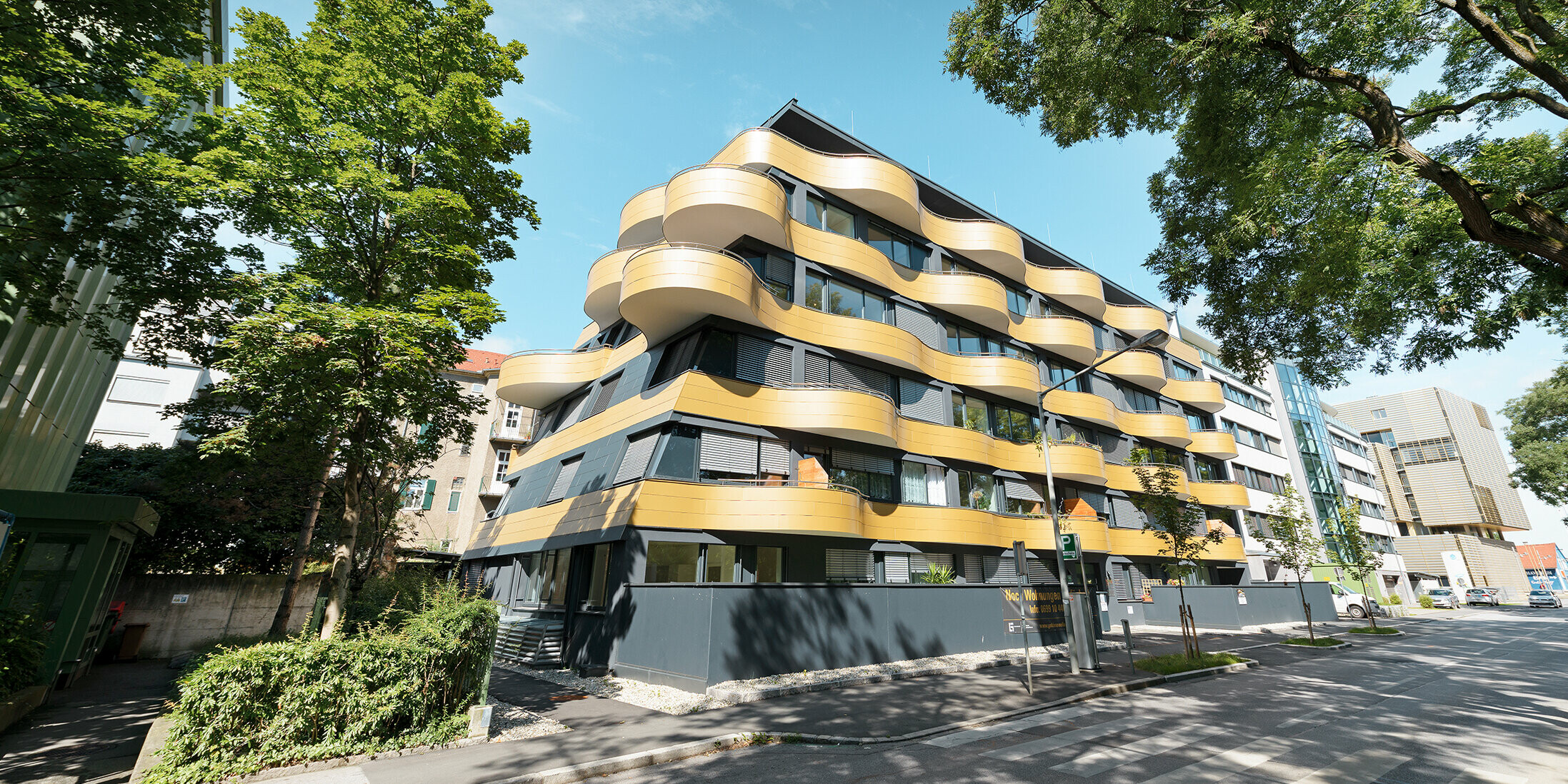 Stanovanjski kompleks »Goldene Welle« v Gradcu v Avstriji, z aluminijastimi kompozitnimi ploščami v zlati barvi, balkoni pa so zaobljeni v obliki valov 