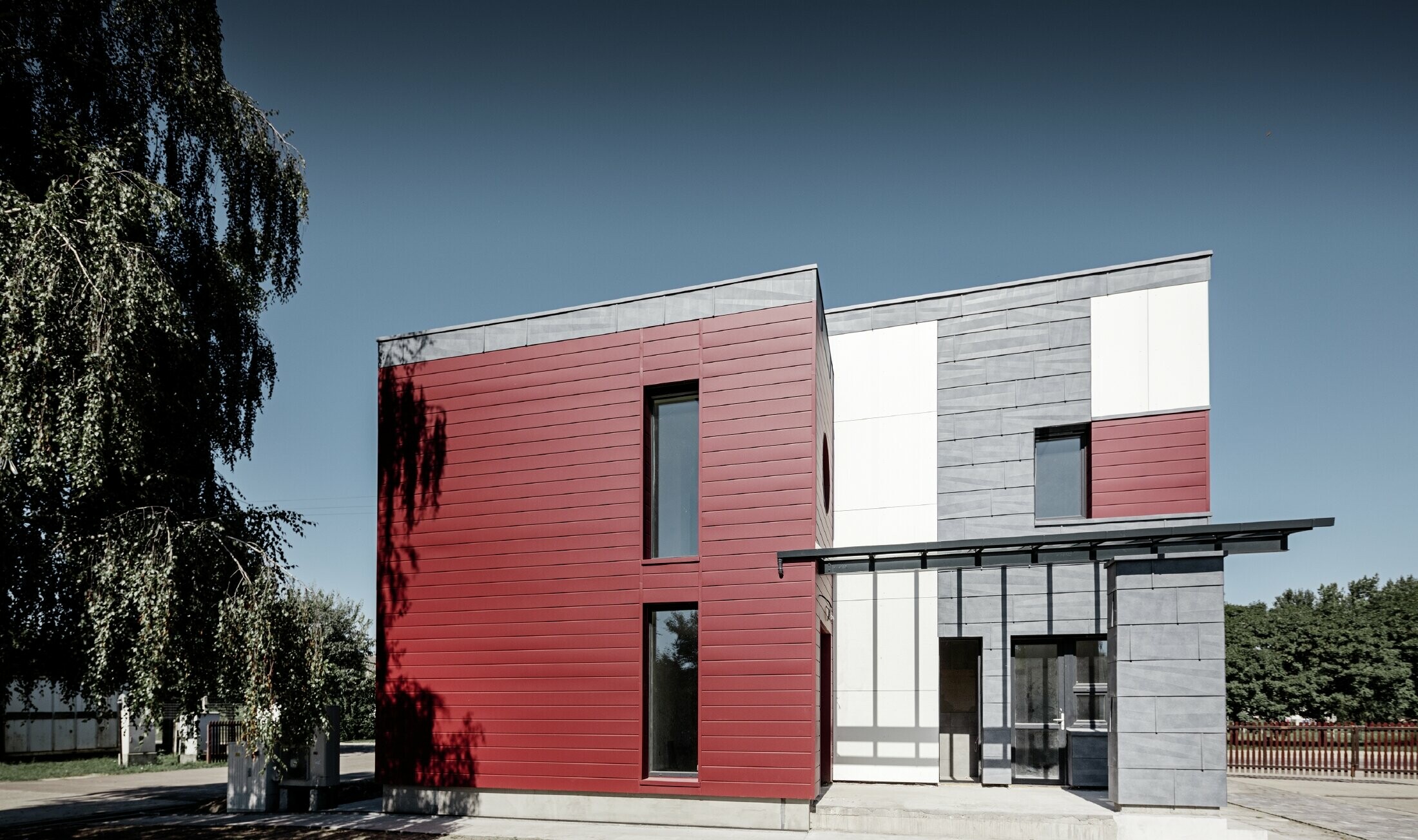 Sodobni poslovni objekt s fasado v rdeči, kamnito sivi in beli barvi z izdelki iz aluminija Siding, fasadnimi paneli FX.12 in aluminijasto kompozitno ploščo PREFA