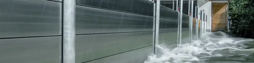 Bližnji posnetek protipoplavne zaščite PREFA iz aluminija, ki je vedno odporna na poplave in ščiti samostojno hišo v ozadju.