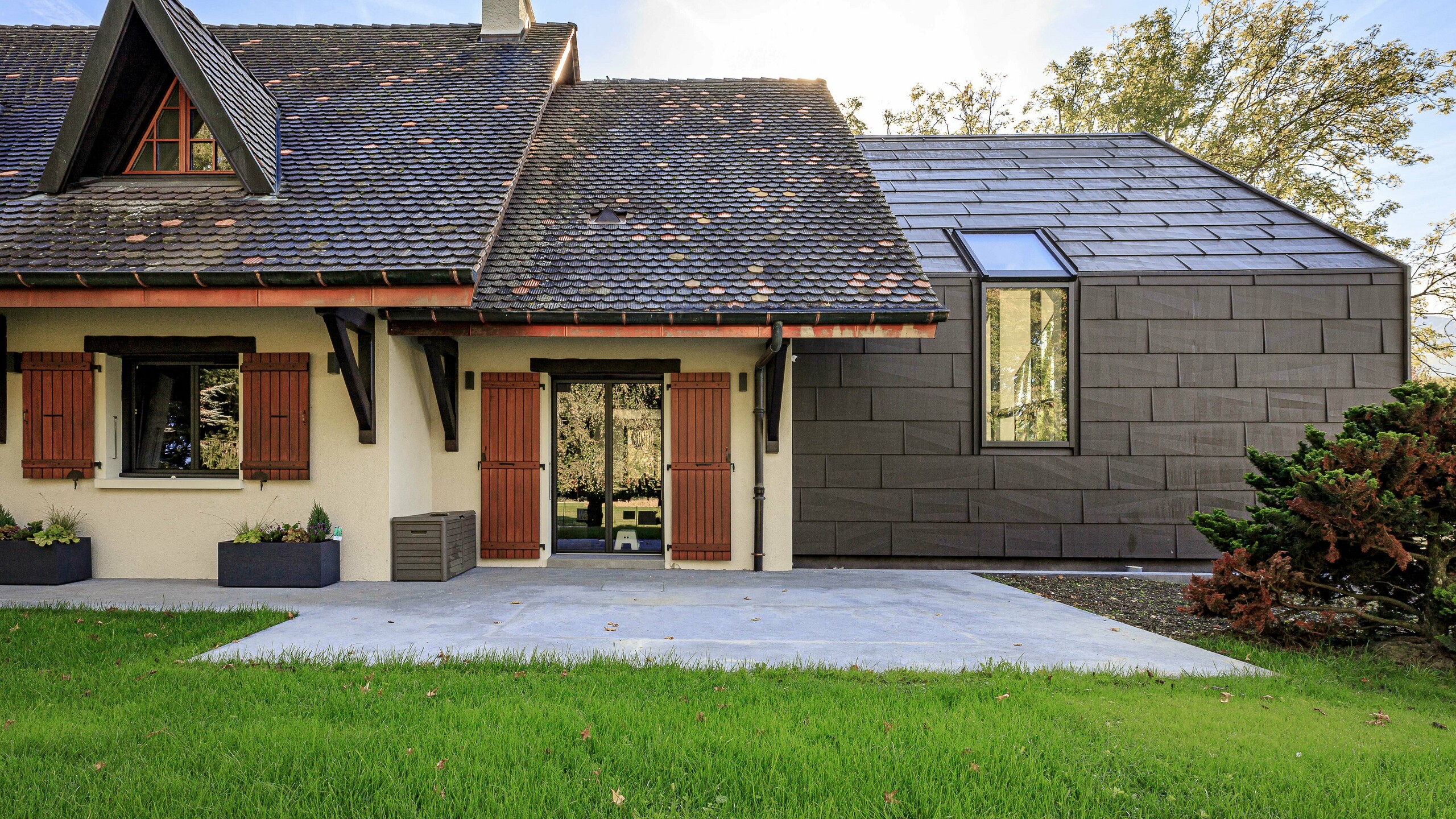 Strešni in fasadni paneli PREFA FX.12 v barvi P.10 anodik rjava kot kontrasten oblikovni element na prizidku enodružinske hiše v Lullyju