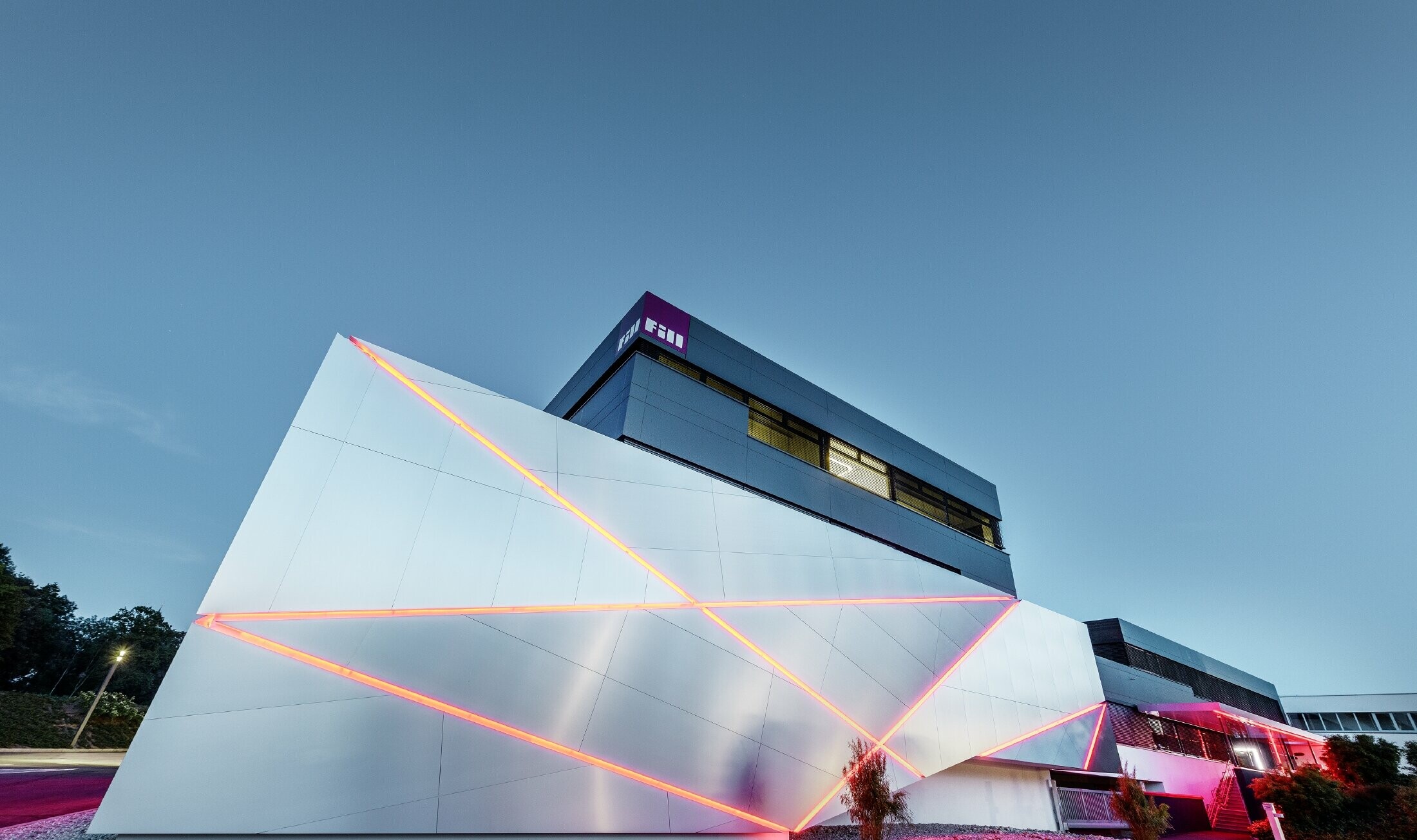 Zgradba podjetja Fill s futuristično fasado iz kompozitnih plošč iz krtačenega aluminija in v ozadju osvetljenimi fugami
