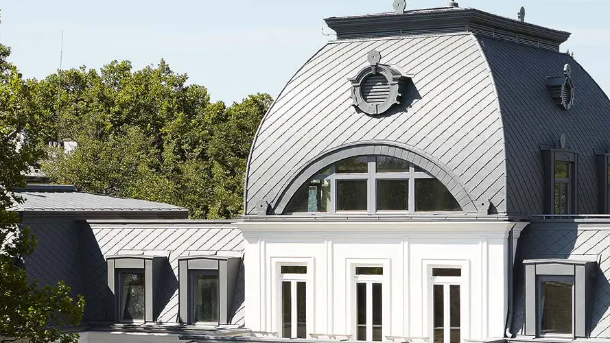 Mansardna streha s kupolo spomeniško zaščitene stavbe, prenovljena s PREFA strešnimi rombi in trakovi PREFALZ v barvi P.10 svetlo siva