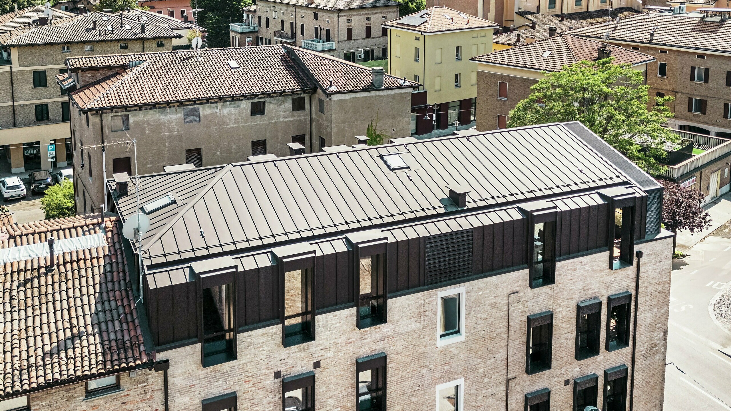 Posodobljena stavba z opečno fasadov Italiji s PREFALZ aluminijasto streho v barvi P.10 testa di moro – estetsko združevanje tradicionalne opekarske arhitekture in moderne, trajne strešne rešitve.