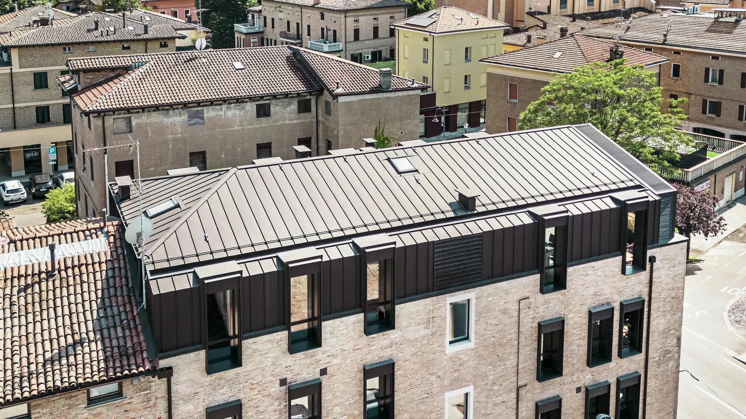 Posodobljena stavba z opečno fasadov Italiji s PREFALZ aluminijasto streho v barvi P.10 testa di moro – estetsko združevanje tradicionalne opekarske arhitekture in moderne, trajne strešne rešitve.