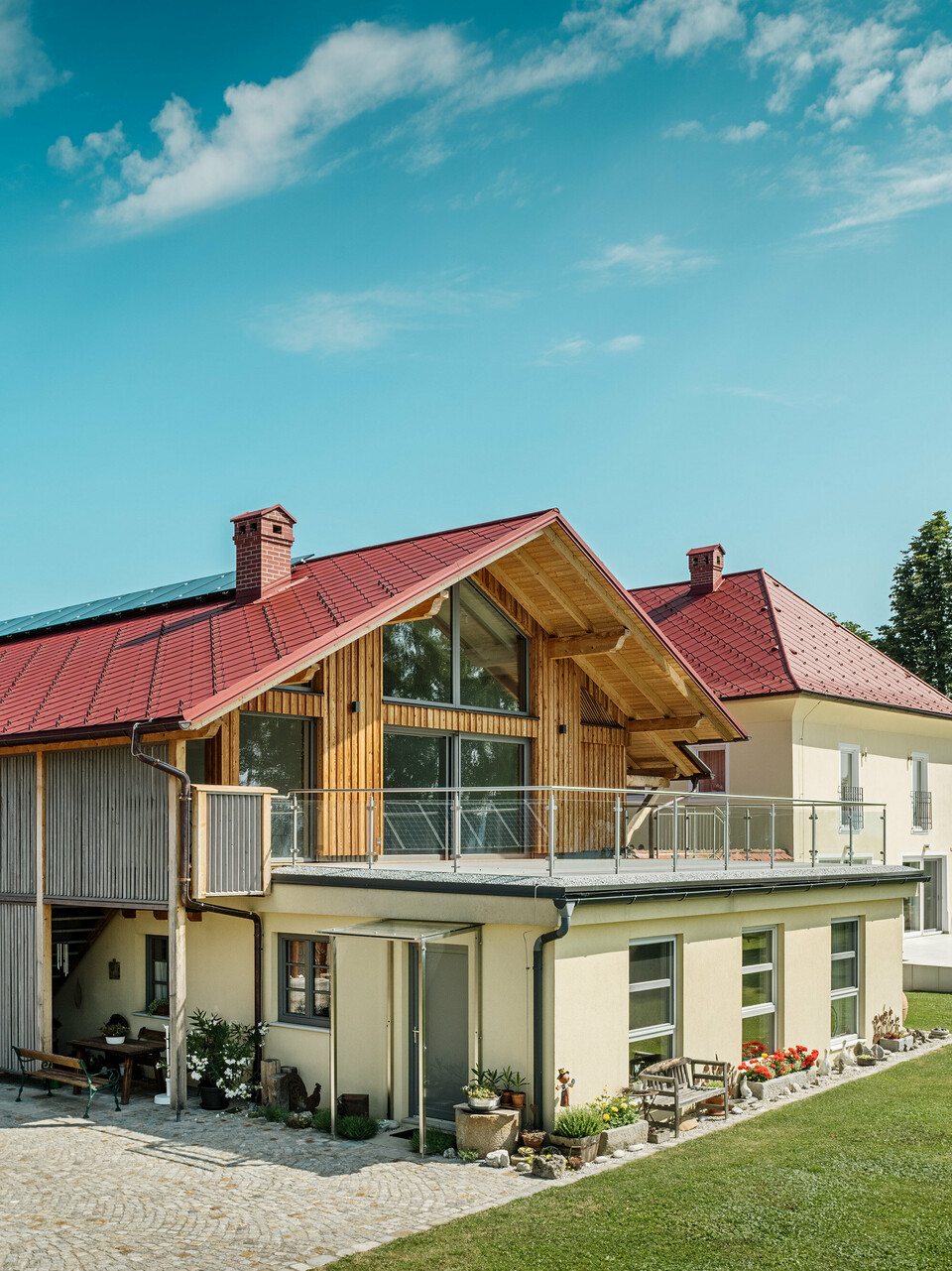 Die beiden sanierten Einfamilienhäuser in Aschach an der Steyr beeindrucken durch ihre harmonische Dachgestaltung. Die PREFA Dachraute 44 x 44 in der Farbe P.10 Oxydrot verleiht ihnen ein markantes, zeitloses Aussehen und bildet einen starken Kontrast zur modernen Holzverkleidung bzw. der gelblichen Putzfassade. Hervorzuheben sind zudem die großflächigen Fenster, welche die Offenheit des Obergeschosses noch verstärken. Das großzügige Grundstück und die gepflegte Gartenlandschaft betonen die gelungene Verbindung von Natur, Tradition und Moderne. Die PREFA Dachrauten sind nicht nur ästhetisch ansprechend, sondern auch äußerst beständig und langlebig – ideal für jedes Wetter.