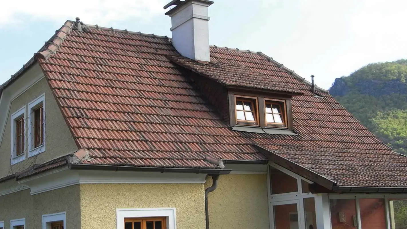 Stara enodružinska hiša pred obnovo strehe z opečnato kritino z grobo ometano rumeno fasado