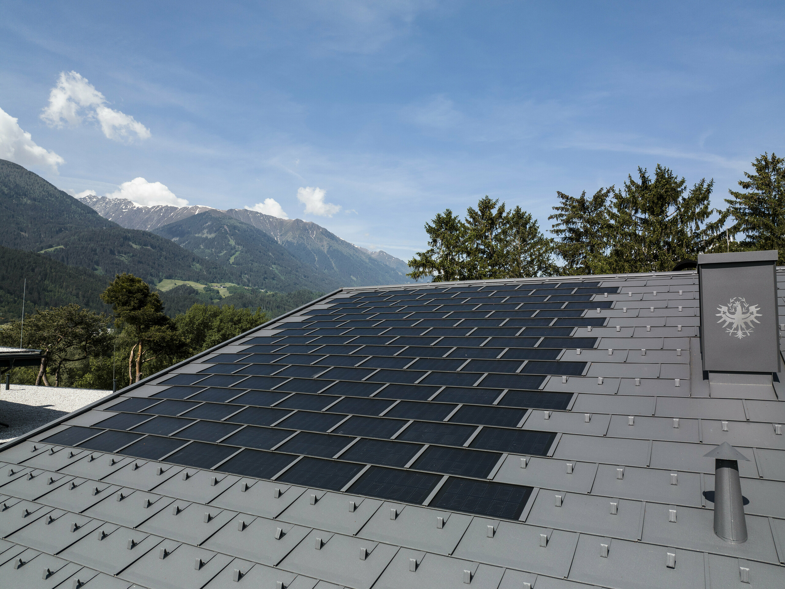 Fotografija strehe na Tirolskem, pokrite s solarno strešno ploščo R.16 PREFA v barvi P.10 temno siva