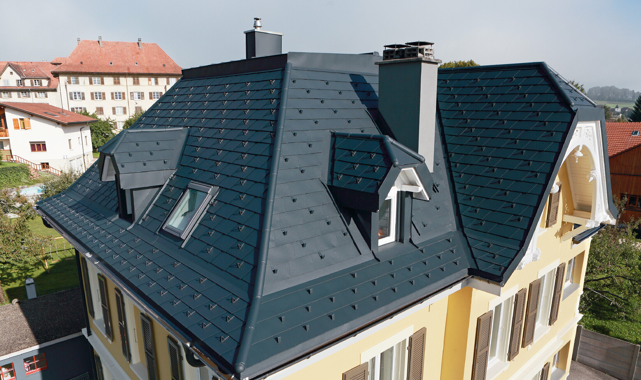 Vila v Švici, streha ima številne žlote in majhne frčade, streha je prekrita z aluminijastimi skodlami PREFA v barvi P.10 antracit