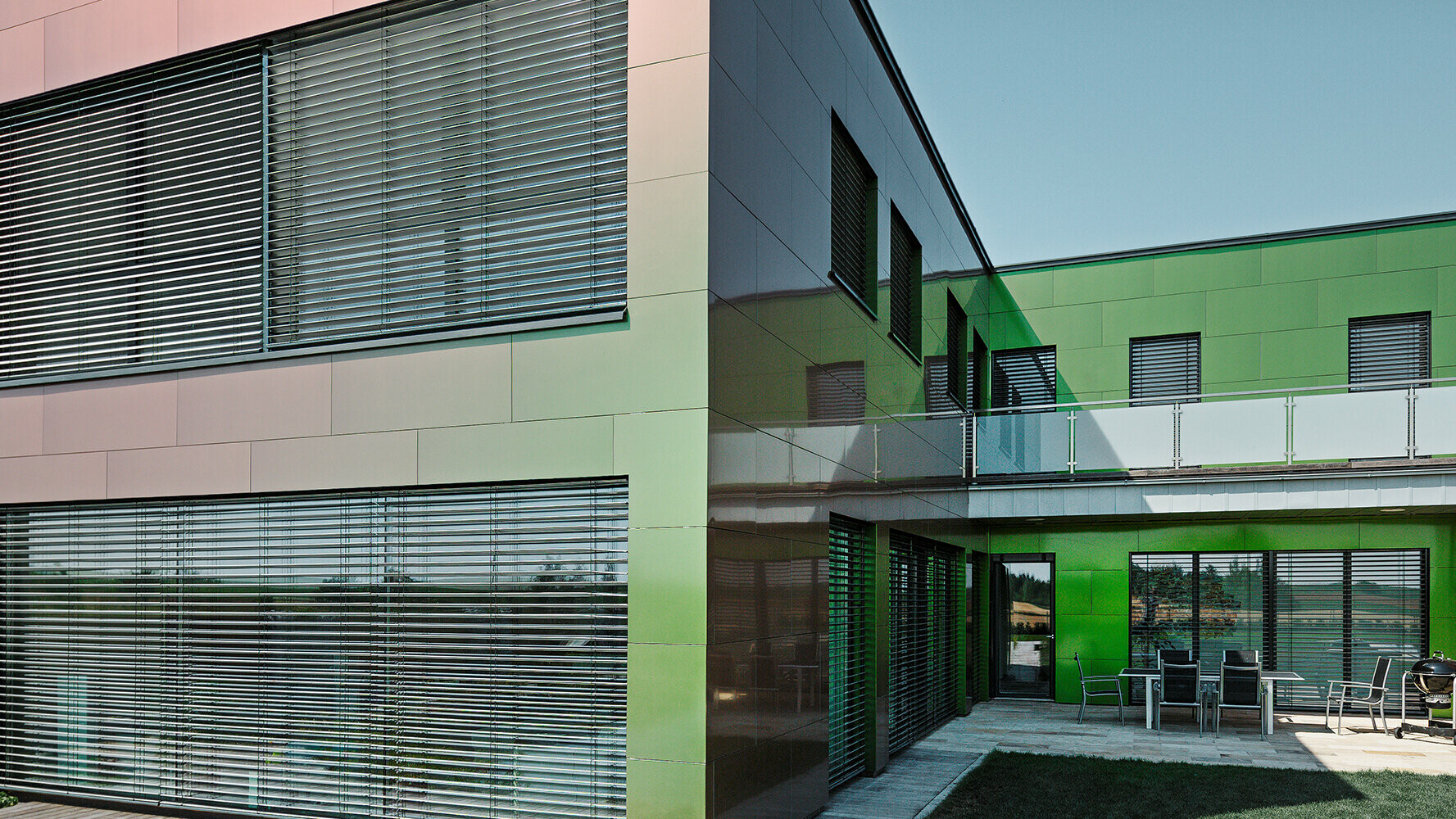 Fasada te stanovanjske hiše iz kompozitnih plošč je glede na svetlobo in perspektivo videti rjava, zelena ali temno vijolična.