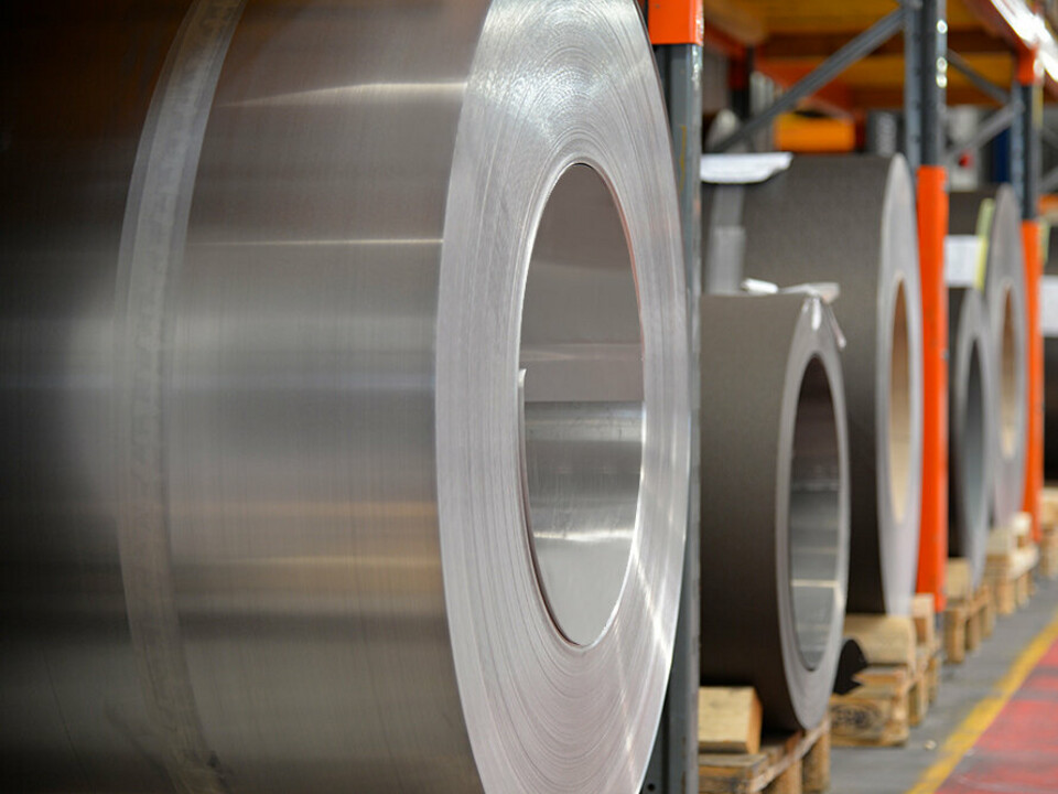 Zvitki aluminija (coils) na lesenih paletah, v ospredju je zvitek aluminija v barvi naravnega aluminija, v ozadju pa drugi trakovi in pločevine iz aluminija.