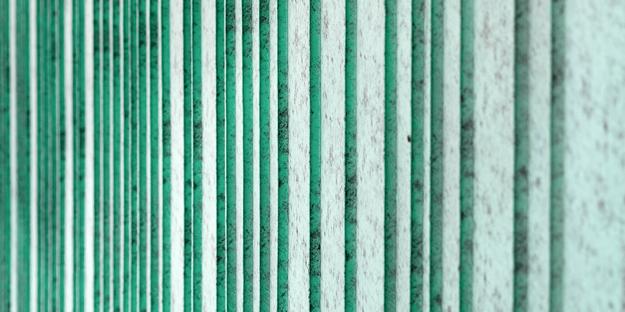 Detailansicht der patinagrünen Aluminium Fassade, rhythmisiert mit unterschiedlich breiten Scharen. Die Farbe erzeugt eine gesprenkelte Optik.