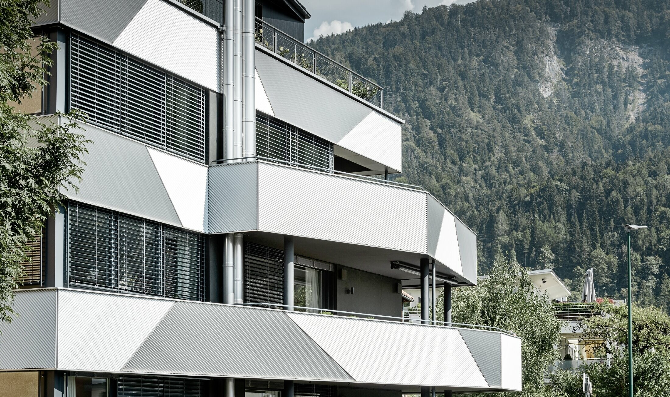 Fassadengestaltung für ein Mehrparteienhaus mit Balkonen und Loggien mit dem PREFA Zackenprofil mit schräger Verlegung.