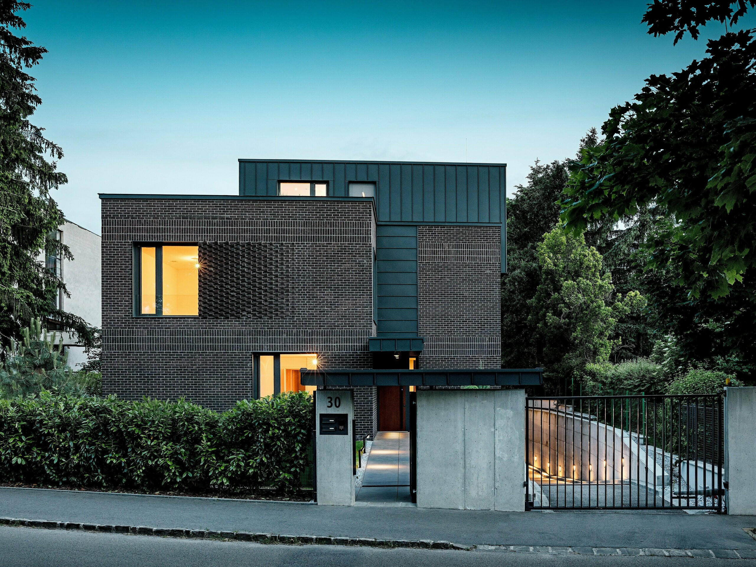 Na sliki je prikazana sodobna večstanovanjska stavba v Budimpešti, katere kubična strešna konstrukcija iz PREFALZ aluminija v barvi P.10 antracit tvori izrazit kontrast z zgodovinskim okoljem. Vertikalni kotni stoječi zgibi ustvarjajo zanimivo igro svetlobe in poudarjajo jasen arhitekturni jezik. Visokokakovostni PREFA aluminijasti izdelki stavbi ne dajejo le elegantnega, brezčasnega videza, temveč prepričajo tudi s svojo dolgo življenjsko dobo, odpornostjo proti vremenskim vplivom in natančno izdelavo. Antracitno obarvana fasada in streha delujeta kot močan magnet za poglede in poudarjata inovativen značaj stavbe.