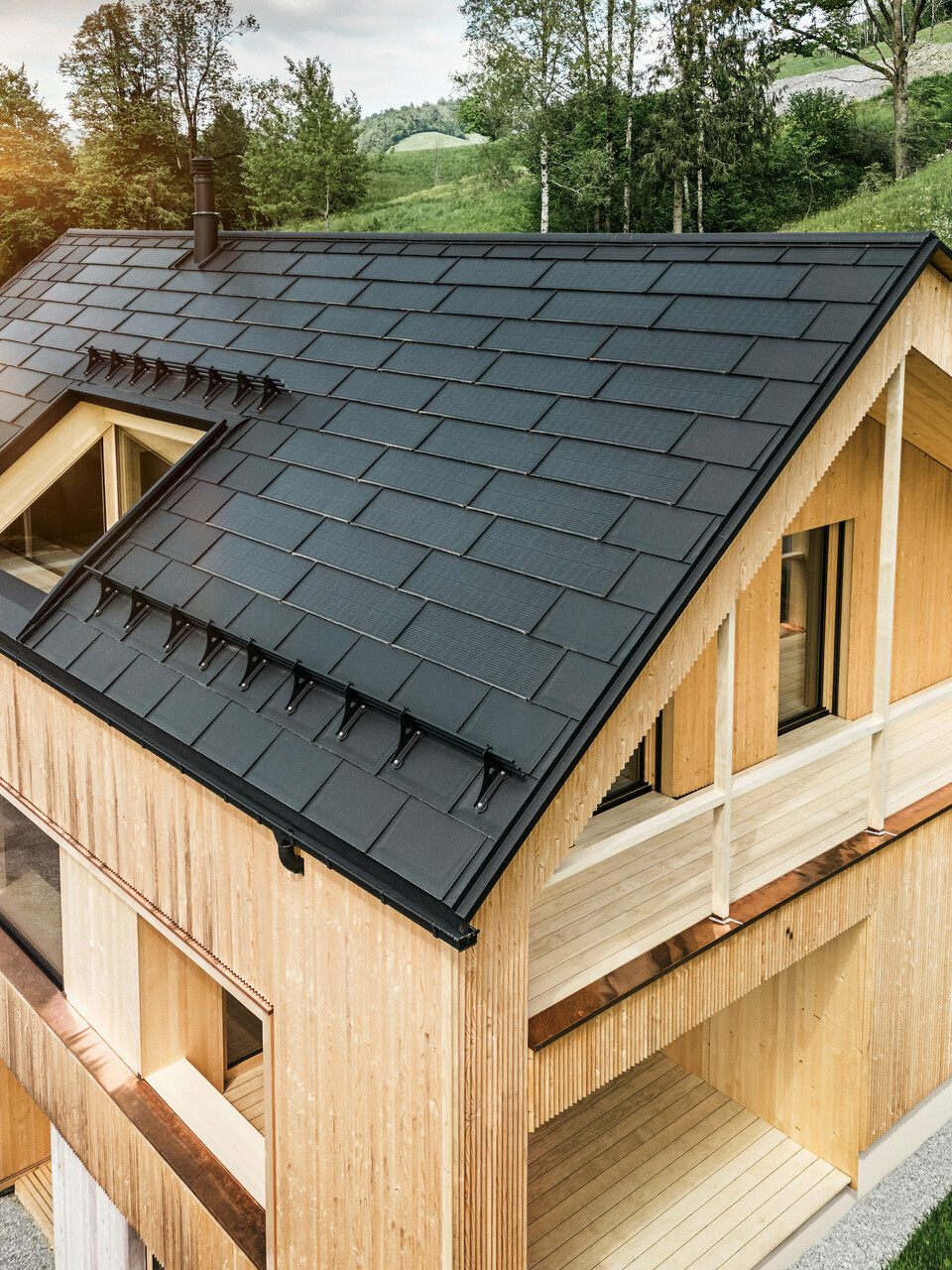 Solarna strešna plošča PREFA in strešna plošča PREFA R.16 nameščeni na enodružinski hiši z leseno fasado v avstrijskem kraju Egg.