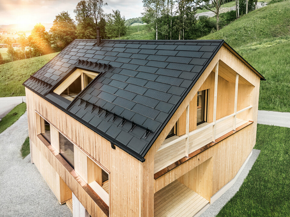 Solarna strešna plošča PREFA in strešna plošča PREFA R.16 nameščeni na enodružinski hiši z leseno fasado v avstrijskem kraju Egg.