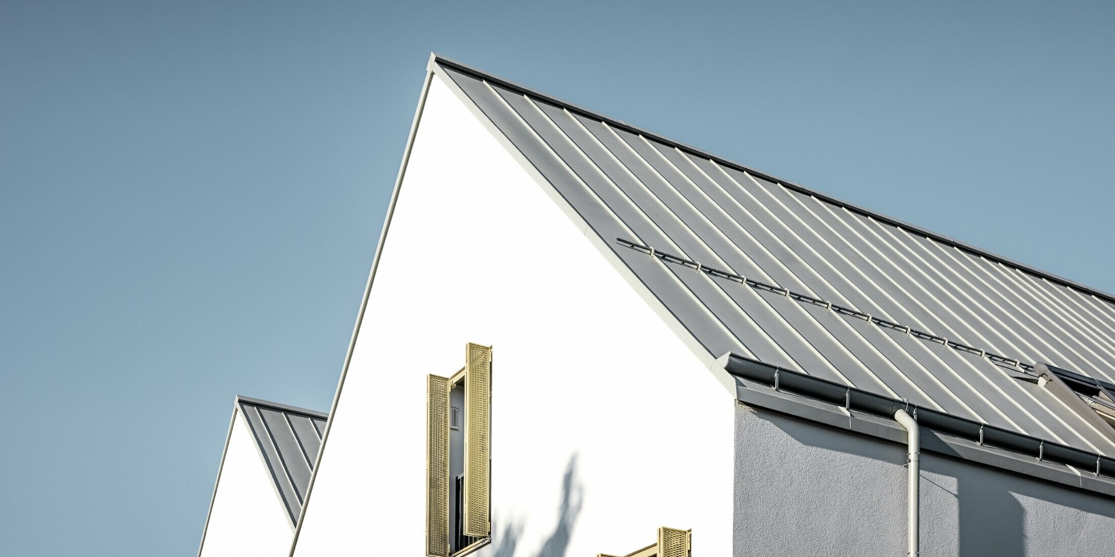 Dvokapna streha brez previsa, obložena s PREFALZ v P.10 cinkovo sivi barvi z ležečim žlebom PREFA