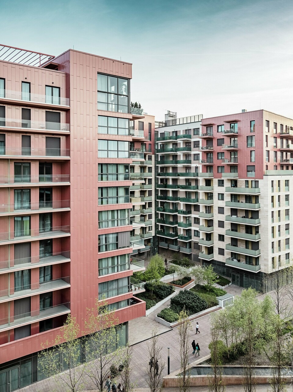 Panoramaaufnahme des Grand Corvin Wohnkomplexes im neugestalteten Corvin-Viertels in Budapest. Die markanten Gebäudeteile sind mit über 800 m² PREFA Siding Fassadenpaneelen in vertikaler Verlegung und Sonderfarbe Lachsmetallic versehen. Die langlebige Aluminiumverkleidung setzt architektonische Highlights, fügt sich harmonisch in die urbane Struktur ein und unterstreicht den hochwertigen, zeitgemäßen Charakter der neuen Wohnanlage entlang der Corvin-Promenade.
