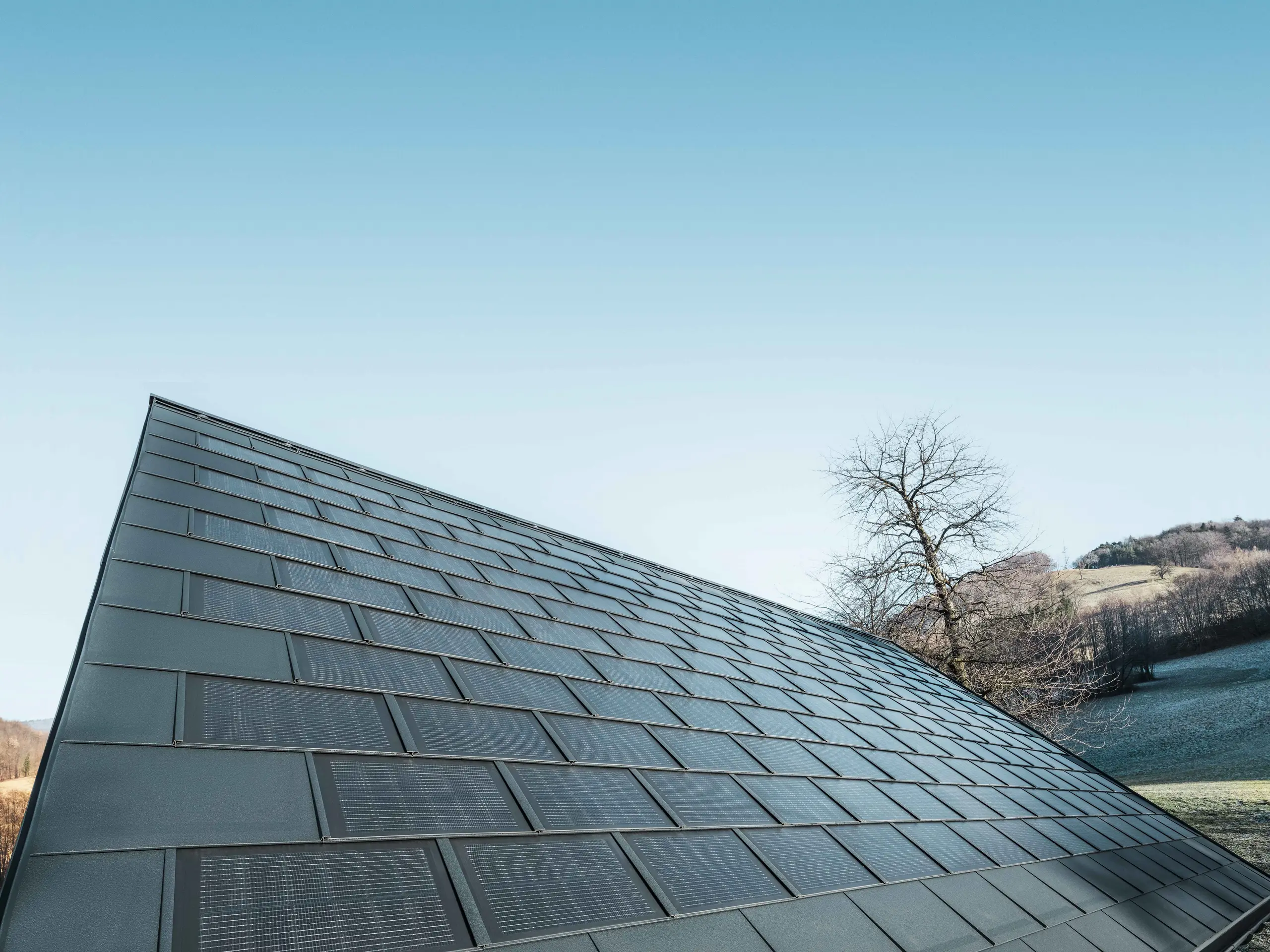 Fotografija površine, obložene s solarno strešno ploščo v antracitni barvi v kombinaciji s strešno ploščo R.16